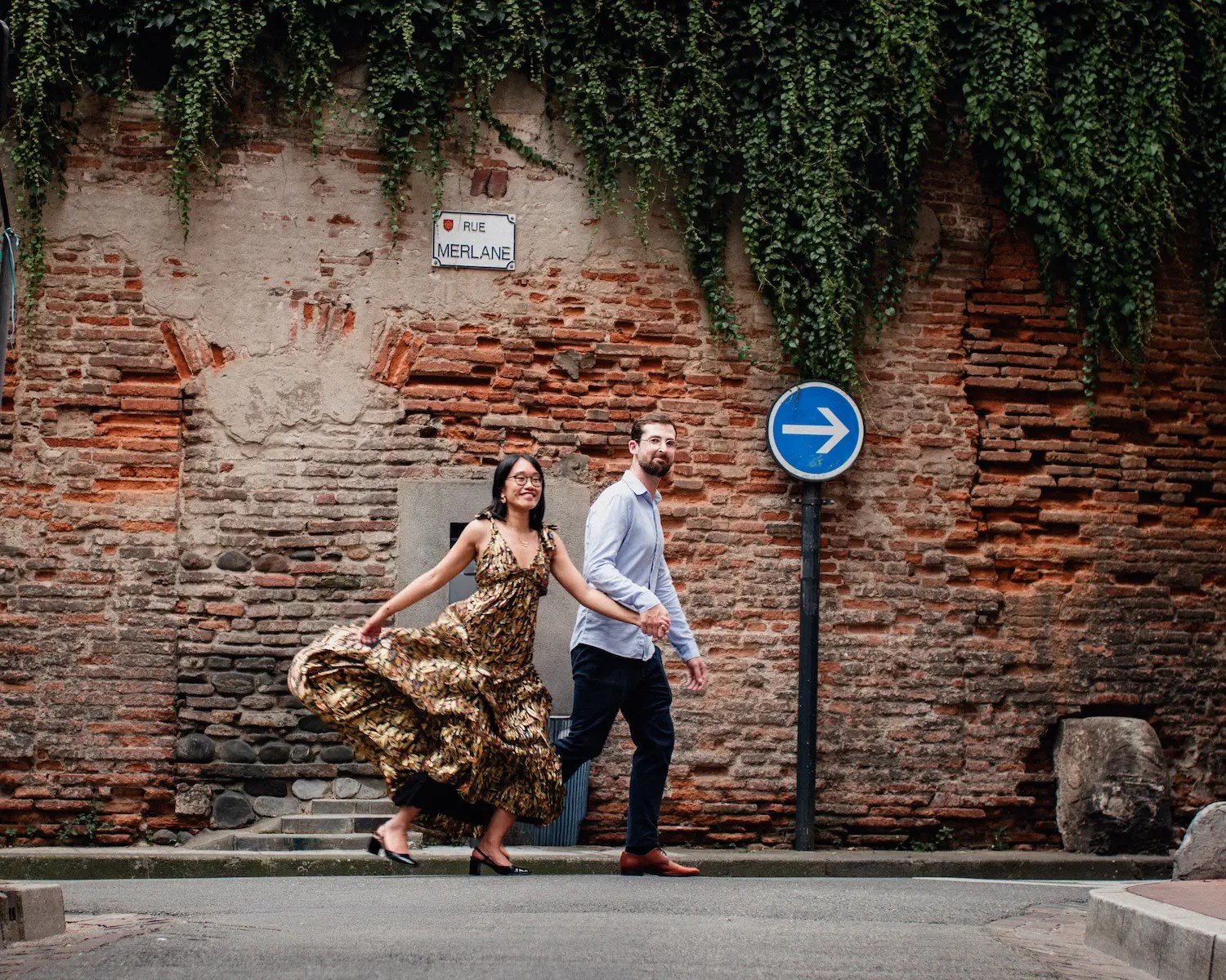 Couple walking and laughing in a pink-brick lane of the Carmes district in Toulouse