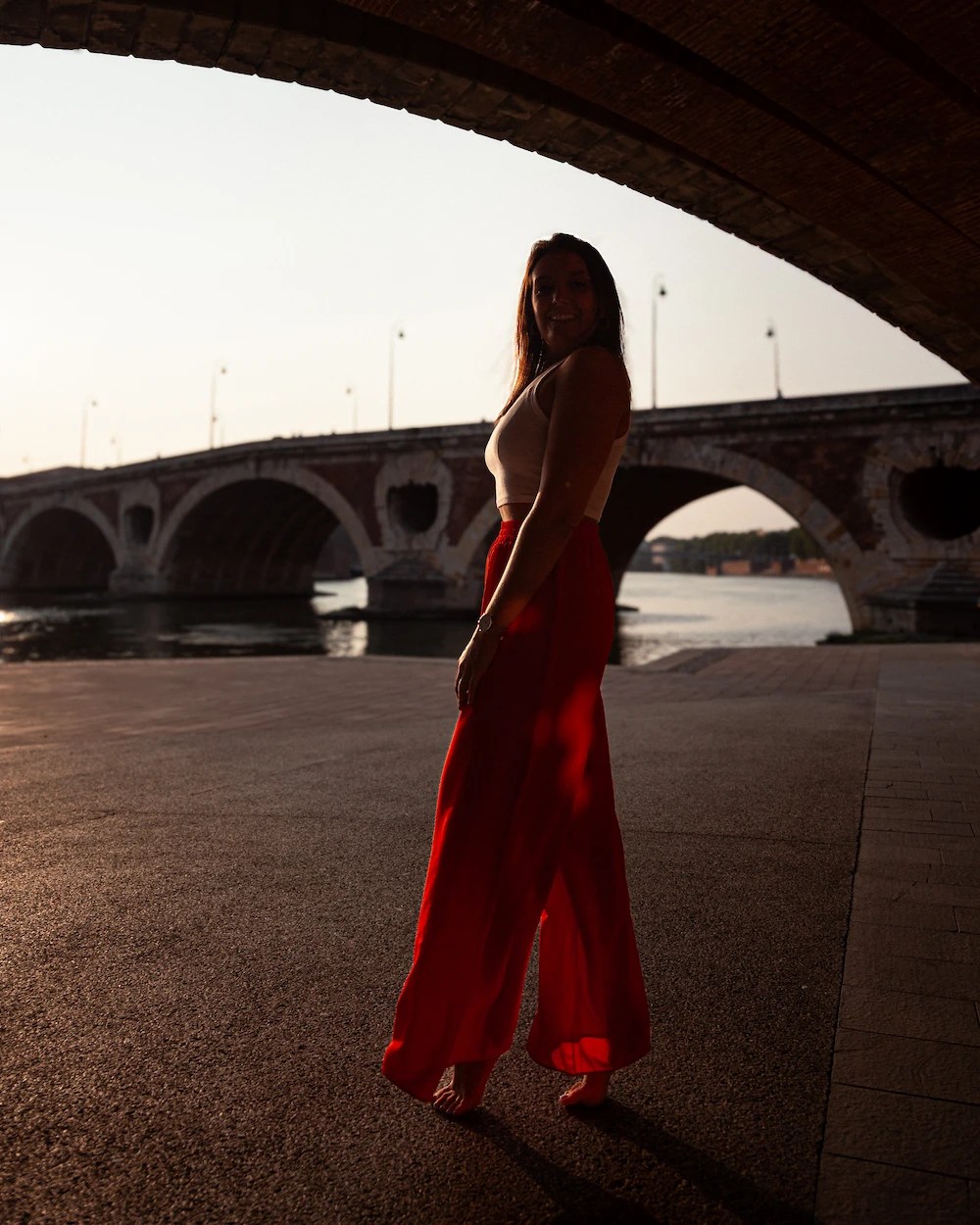 Woman in a red dress by the Pont Neuf in Toulouse at sunset